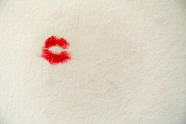 Red lipstick kiss mark on white plaster wall